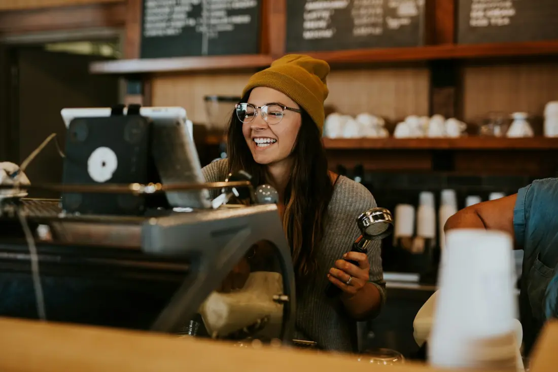 Barista serving behind a busy café counter