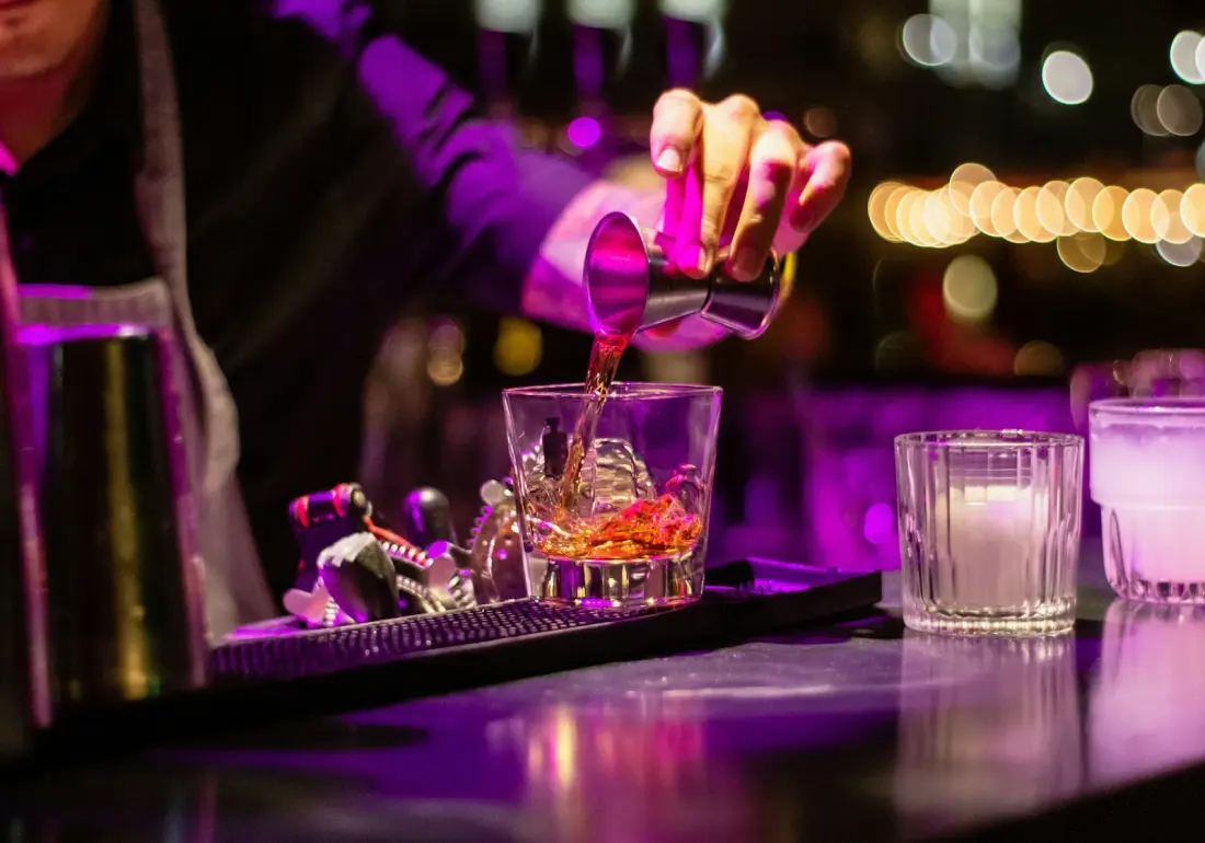 Bartender pouring a cocktail at a dimly lit bar