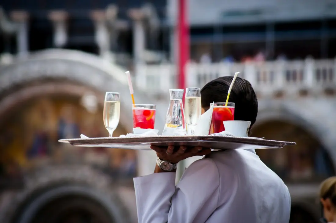 Waiter carrying a tray of drinks to guests